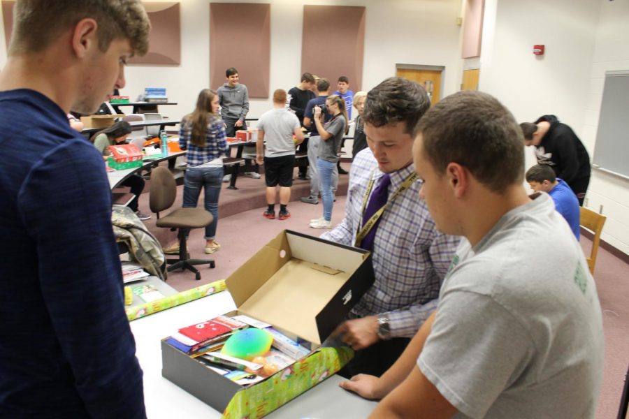 Topping It Off Mr. Christy helps senior Ryan Broad and sophomore Shayne Gumpp put the finishing touches on their shoebox. Broad said working with a group enhanced the experience because they were able to get a lot more done and have fun while doing it.