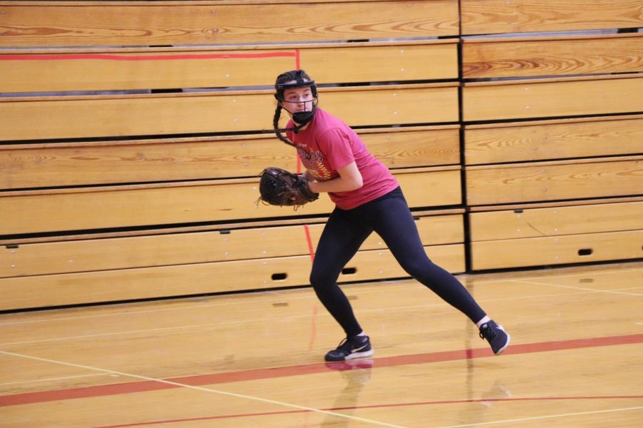 Paige Gresgott practices throwing and catching the softball with her teammates in the Rock Box. When the weather outside is awful, many spring sports teams have to relocate inside for practice.